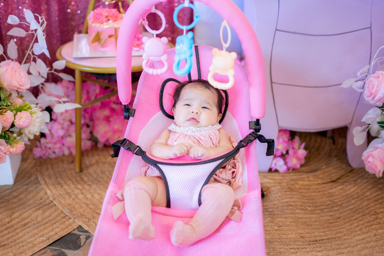 hero-img-02 Charming baby girl in a pink bouncer surrounded by flowers, perfect for family and lifestyle themes.
